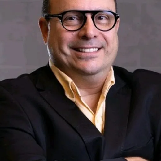 Flavio Nafell de terno e óculos, braços cruzados