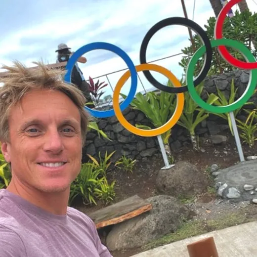 Stan Fiess sorrindo, com os arcos olímpicos ao fundo