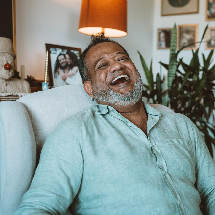 Marcio Libar rindo, sentado em uma poltrona clara